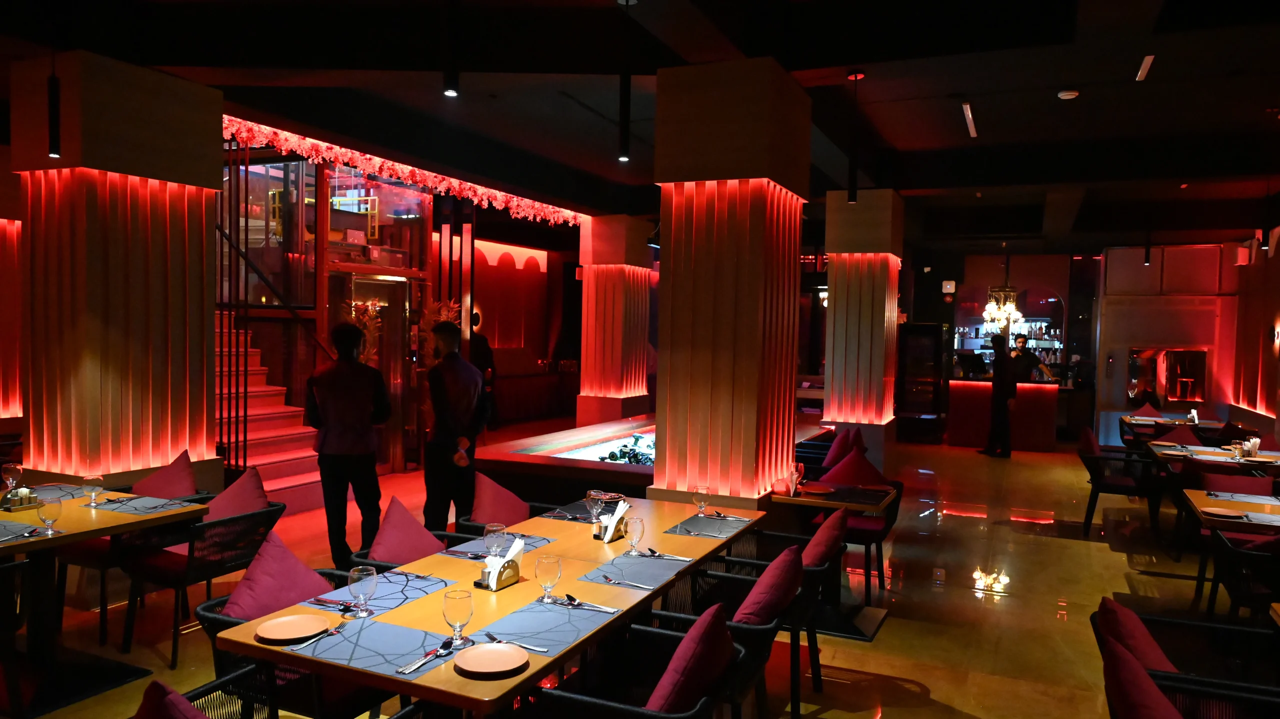 Premium dining table setup inside a luxury restaurant near Islamabad Airport with red ambient lighting.